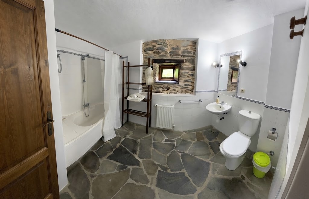 El Buxo: baño con bañera y ventana en muro de piedra.