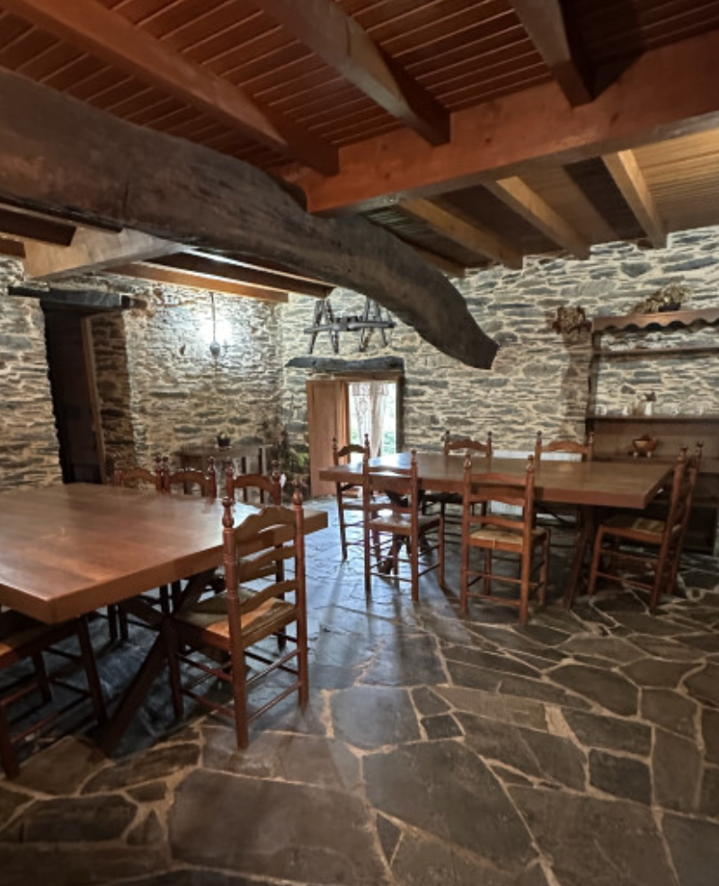 Mesas y sillas de madera en el comedor de piedra.